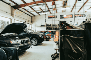 Interior shop view of High Tech Automotive with vehicles being repaired by mechanics.